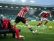 Pitch-level photo under floodlights: empty bench seat with a red bib hinting at a
