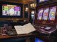 Photograph of a casino slot machine with chips, a calculator, and blurred notes implying